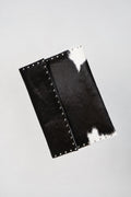 Black and white Cowhide laptop case by Violeta with silver stud trim, front view showing the flap