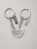 Two silver split-heart keychains with engraved text reading 'BEST FRIENDS FOREVER' and personalized name tags, displayed on a light gray background.