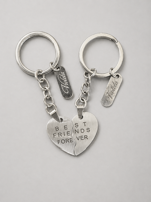 Two silver split-heart keychains with engraved text reading 'BEST FRIENDS FOREVER' and personalized name tags, displayed on a light gray background.