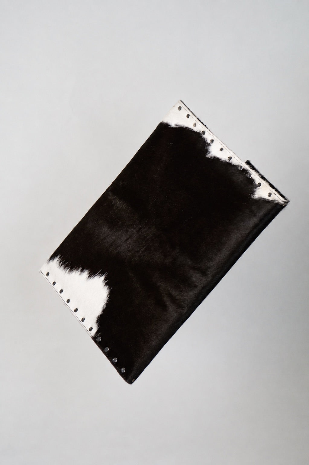Back of the black and white Cowhide laptop case with silver studs along the edges