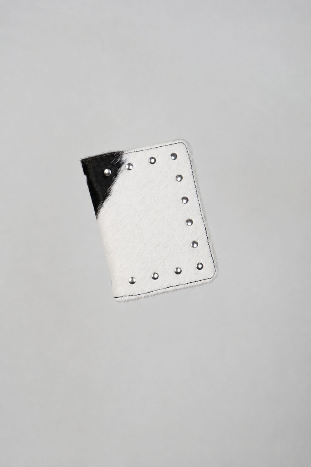Black and white Cowhide passport case by Violeta with silver studs, front view