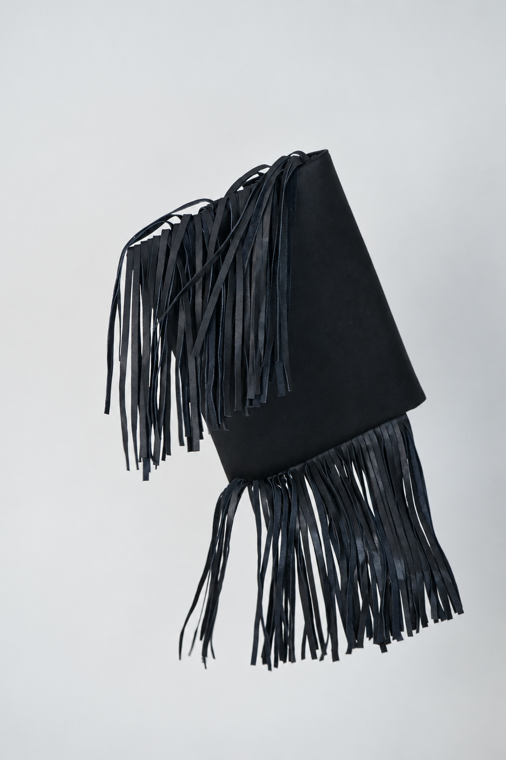 Black leather Shalom Fringe laptop case by Violeta floating at an angle, showing the long fringe falling from the side
